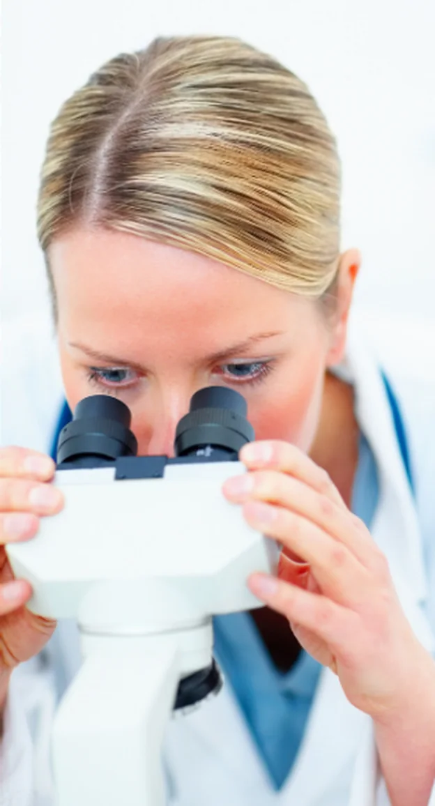 A researcher examining samples under a microscope